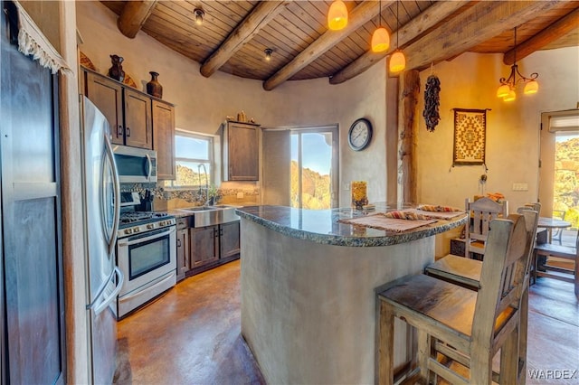 kitchen featuring a sink, a kitchen breakfast bar, finished concrete floors, stainless steel appliances, and wood ceiling