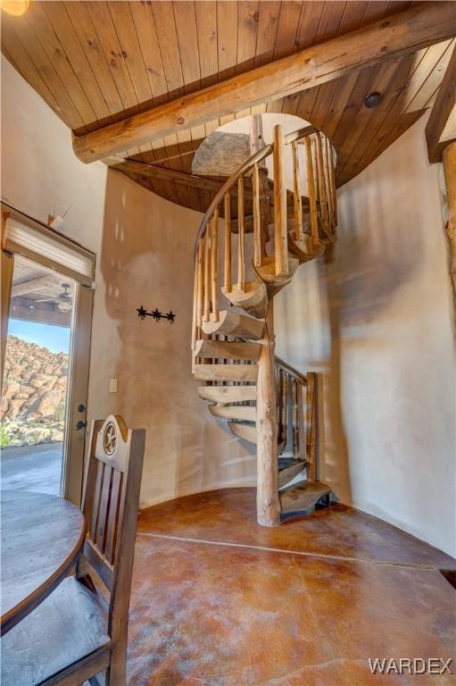 stairway with concrete floors, beam ceiling, and wood ceiling