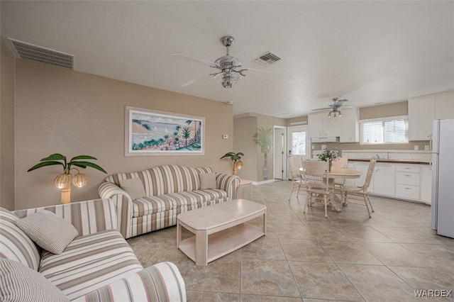 living area with light tile patterned floors, ceiling fan, and visible vents