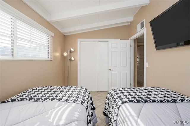 bedroom featuring vaulted ceiling with beams, a closet, and visible vents