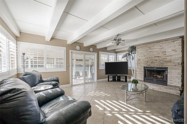 living area featuring beam ceiling, a fireplace, light tile patterned floors, a ceiling fan, and baseboards