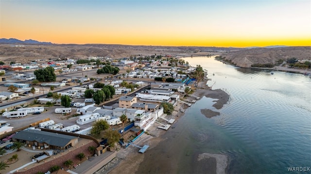 aerial view at dusk featuring a water view