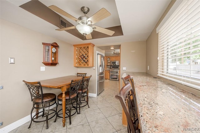 dining space featuring a ceiling fan, baseboards, and light tile patterned floors