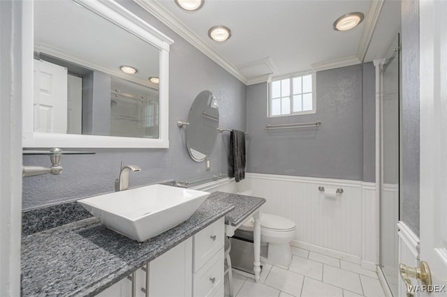 bathroom with wainscoting, toilet, ornamental molding, tile patterned floors, and vanity