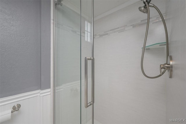 full bathroom with a stall shower and a wainscoted wall