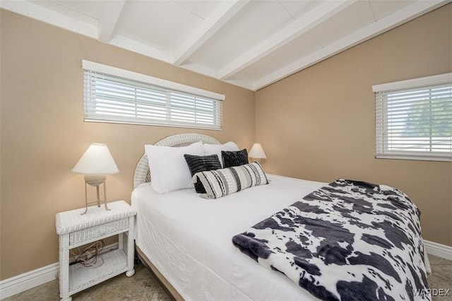 bedroom with vaulted ceiling with beams, multiple windows, and baseboards