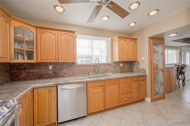 kitchen featuring light stone counters, stove, glass insert cabinets, a sink, and dishwasher