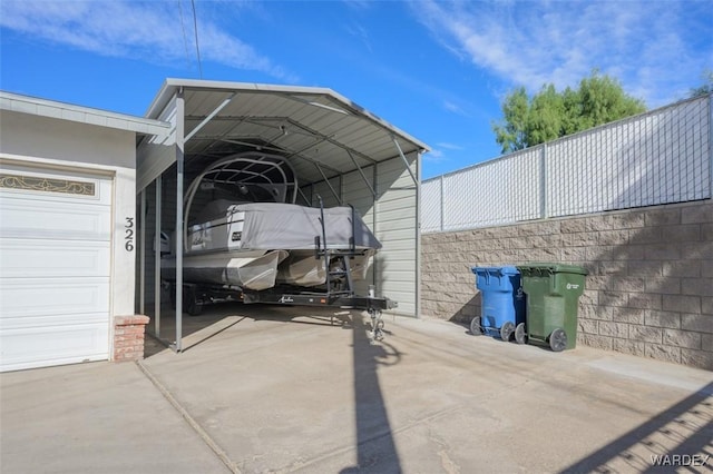 view of parking / parking lot featuring a garage, driveway, fence, and a detached carport