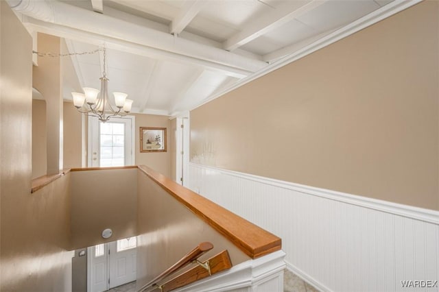 corridor featuring a wainscoted wall, a chandelier, an upstairs landing, and vaulted ceiling with beams