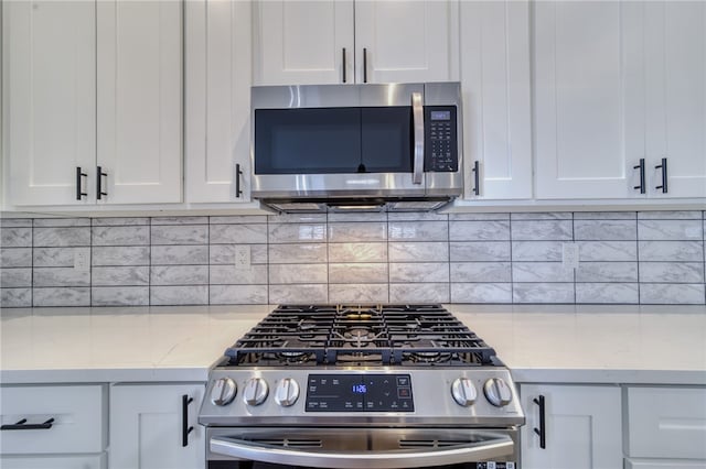 2339 E Calle Madrid, Fort Mohave, AZ 86426 - kitchen featuring appliances with stainless steel finishes, white cabinetry, backsplash, and light stone countertops