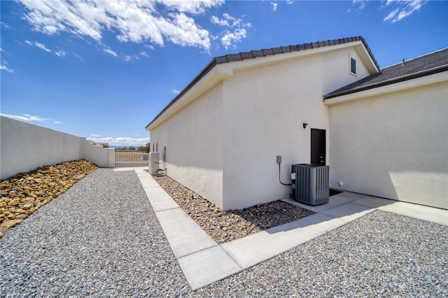 2339 E Calle Madrid, Fort Mohave, AZ 86426 - view of home's exterior with stucco siding, central AC, fence, and a gate