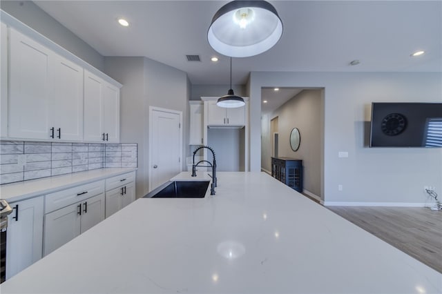 2339 E Calle Madrid, Fort Mohave, AZ 86426 - kitchen with a sink, white cabinetry, tasteful backsplash, wood finished floors, and pendant lighting