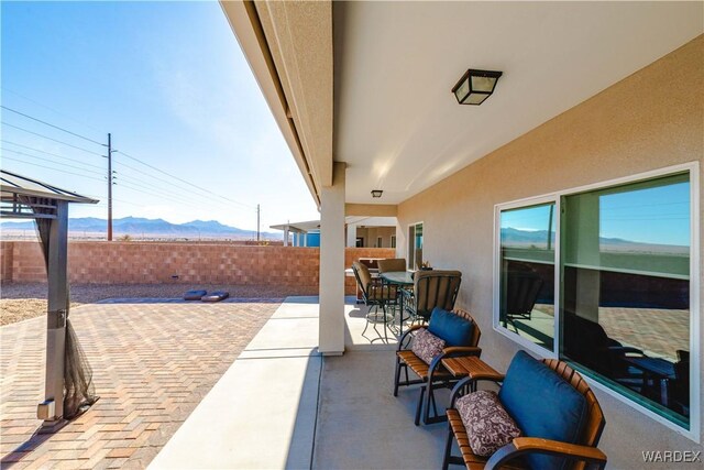 view of patio / terrace featuring outdoor dining space, a fenced backyard, and a mountain view