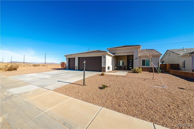 prairie-style house featuring stone siding, driveway, an attached garage, and stucco siding