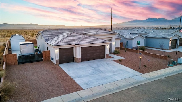 ranch-style house featuring driveway, a tile roof, an attached garage, fence, and a mountain view