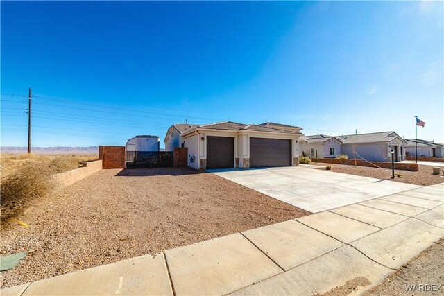 single story home featuring an attached garage, fence, driveway, stone siding, and stucco siding