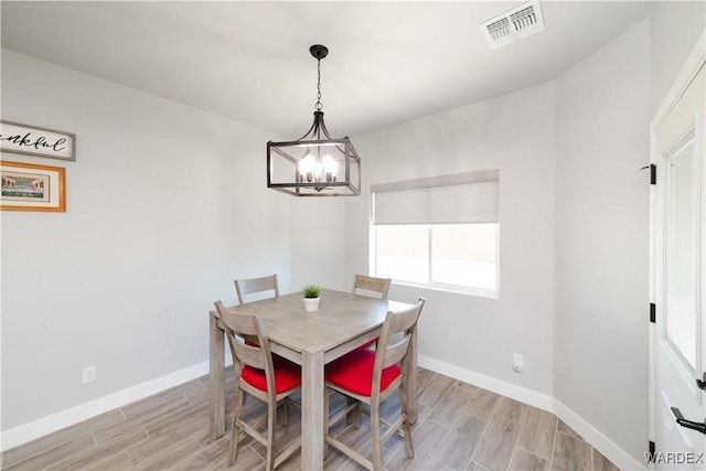 dining room featuring a notable chandelier, visible vents, baseboards, and wood tiled floor