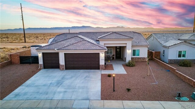 view of front facade featuring an attached garage, a mountain view, fence, concrete driveway, and stone siding