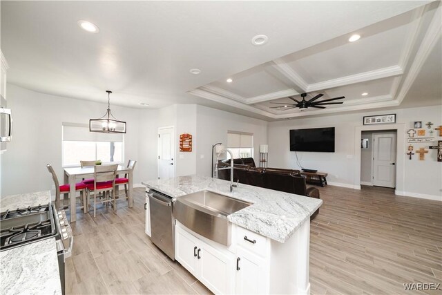 kitchen featuring a kitchen island with sink, stainless steel appliances, a sink, white cabinets, and hanging light fixtures