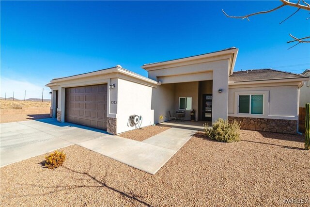 view of front of property featuring a garage, stone siding, concrete driveway, and stucco siding