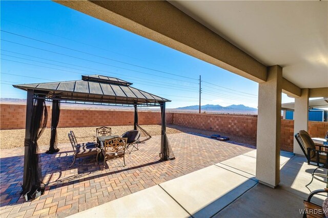 view of patio featuring a fenced backyard, a mountain view, and a gazebo