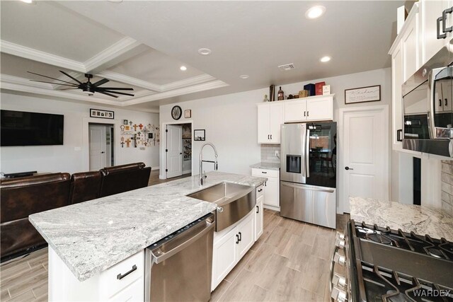 kitchen featuring appliances with stainless steel finishes, open floor plan, a sink, and an island with sink