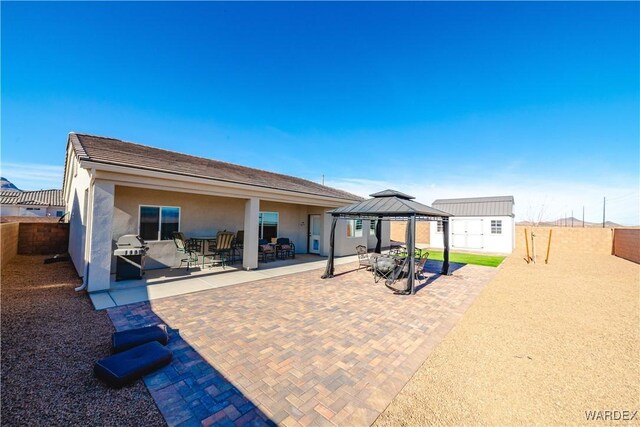 view of patio / terrace featuring a fenced backyard, an outdoor structure, grilling area, and a gazebo