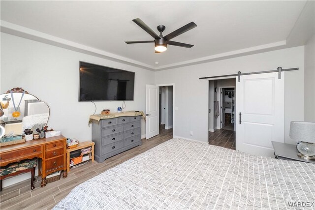 bedroom featuring a barn door, wood finish floors, and a ceiling fan