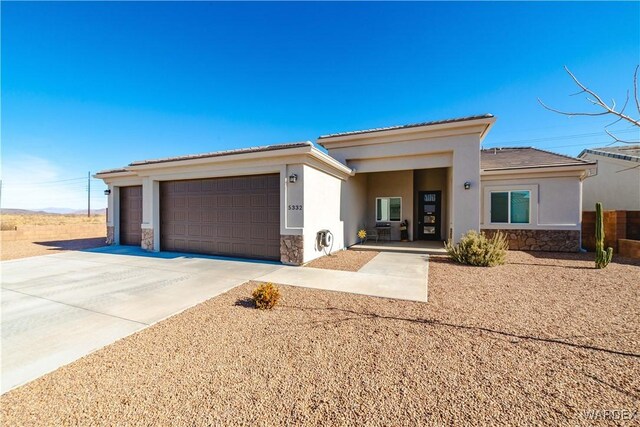 prairie-style house featuring a garage, stone siding, concrete driveway, and stucco siding