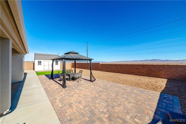 view of patio / terrace featuring a fenced backyard, an outbuilding, and a gazebo