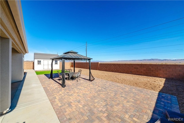 view of patio / terrace featuring a fenced backyard, a gazebo, an outdoor structure, and a shed
