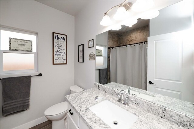 full bathroom with baseboards, a shower with shower curtain, toilet, vanity, and a chandelier