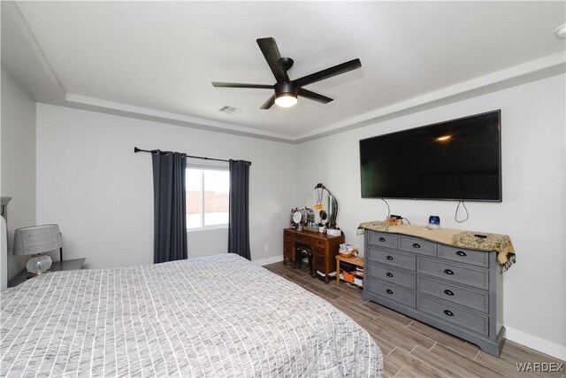 bedroom featuring a ceiling fan, wood tiled floor, visible vents, and baseboards