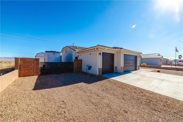 view of front facade with concrete driveway, fence, an attached garage, and stucco siding