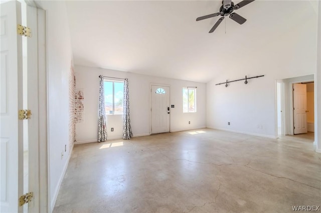 foyer entrance with finished concrete floors, vaulted ceiling, baseboards, and a ceiling fan