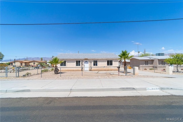 view of front of property with a fenced front yard, concrete driveway, and stucco siding