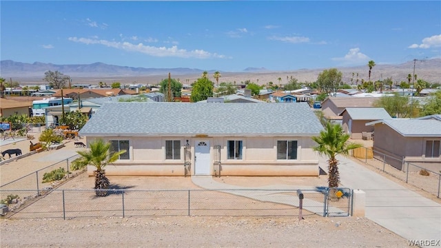 single story home featuring a fenced front yard, stucco siding, a shingled roof, a gate, and a mountain view