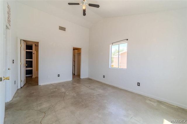 unfurnished bedroom featuring a walk in closet, high vaulted ceiling, visible vents, concrete flooring, and baseboards