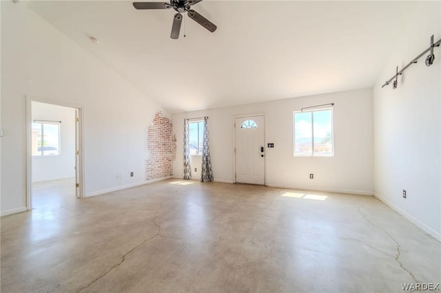 interior space featuring vaulted ceiling, concrete floors, baseboards, and ceiling fan