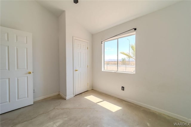 unfurnished bedroom featuring vaulted ceiling, concrete floors, and baseboards