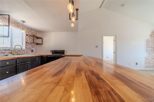 kitchen with decorative light fixtures, black electric range oven, a sink, brick wall, and dark cabinetry