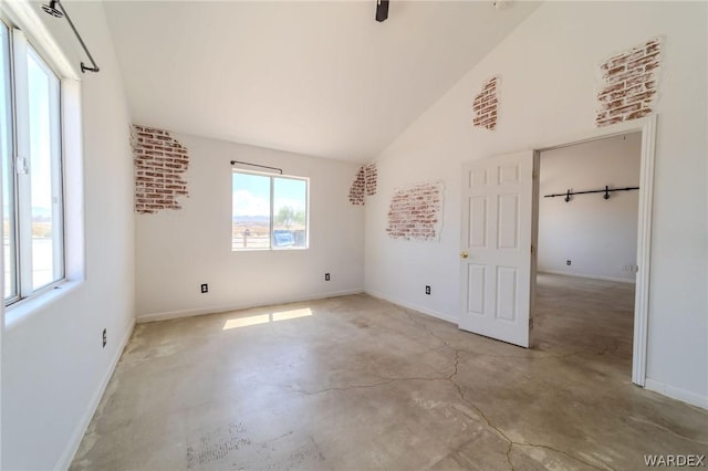 unfurnished bedroom featuring vaulted ceiling, concrete floors, and baseboards