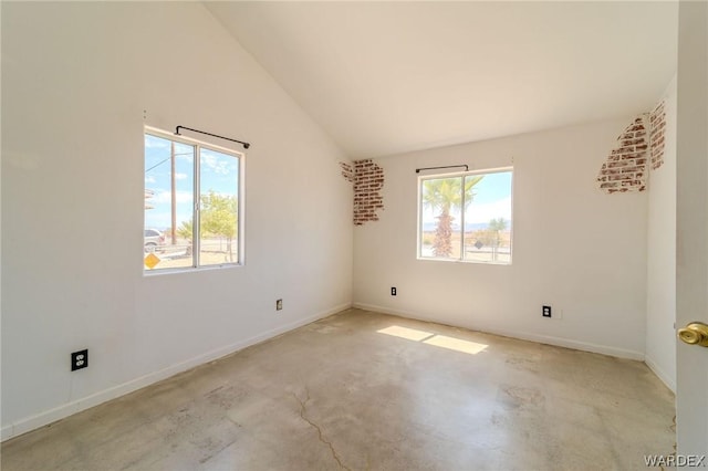 empty room featuring lofted ceiling, concrete floors, and baseboards