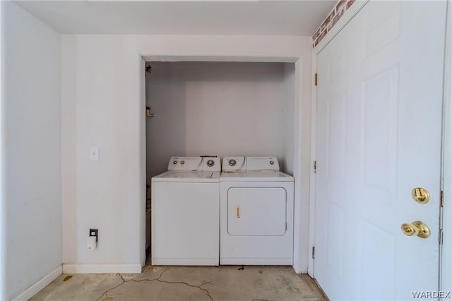 laundry area with laundry area, washing machine and dryer, and baseboards