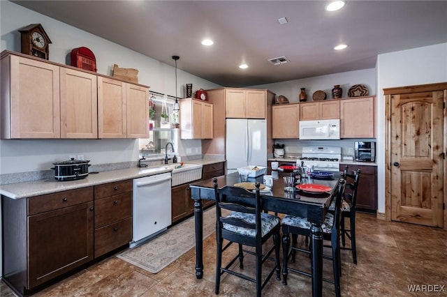 kitchen featuring a sink, visible vents, light countertops, light brown cabinetry, and white appliances