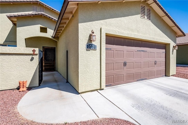 view of home's exterior with stucco siding, concrete driveway, and an attached garage