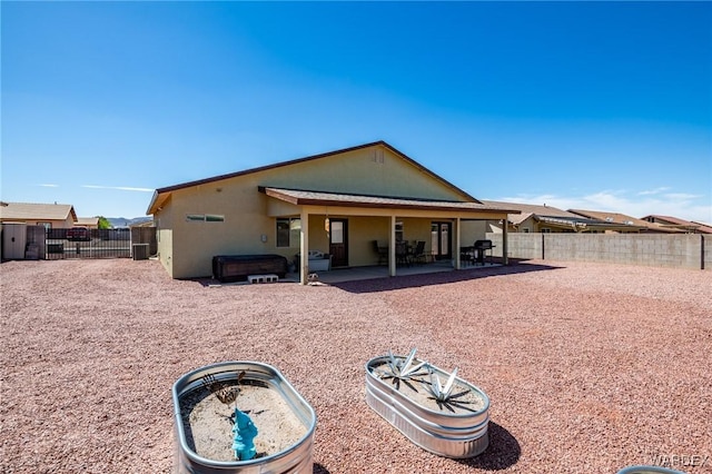 rear view of house featuring stucco siding, a patio, a jacuzzi, and a fenced backyard