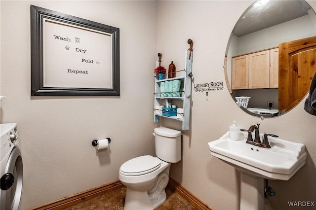 bathroom featuring toilet, washer / dryer, and baseboards