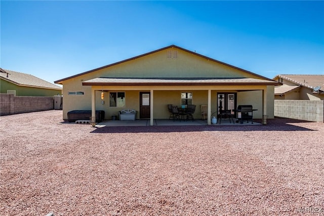rear view of house featuring stucco siding, a patio, a jacuzzi, and a fenced backyard
