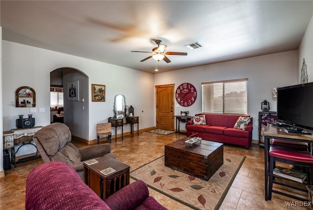 living room with arched walkways, tile patterned floors, baseboards, visible vents, and a ceiling fan